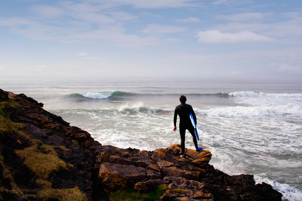 Surfer looks at waves at Tullan Strand, Bundoran, County Donegal, Ireland